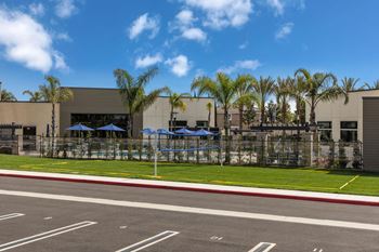 a building with umbrellas and palm trees in front of itat Westbury Apartments, Rancho Cucamonga